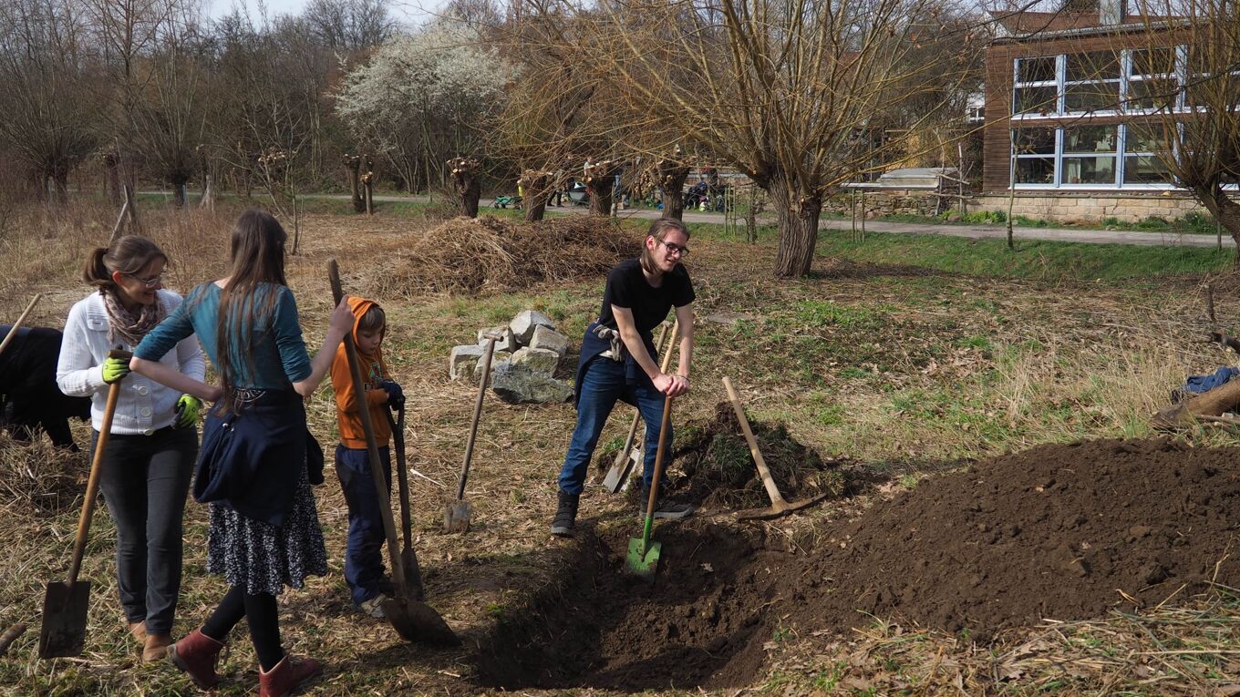 Kinder und Jugendliche graben ein Loch für ein Zauneidechsenbiotop.