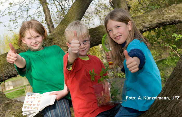 Drei Kinder blicken in die Kamera und zeigen den Daumen nach oben.