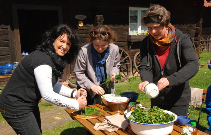 Drei Teilnehmer:innen eines Seminars bereiten Essen im Freien zu.