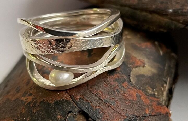 Ein geschwungener, goldener Ring mit einer Perle. - Link: Vernissage „Kunst trifft… Flussperlmuschel“ in Bad Elster