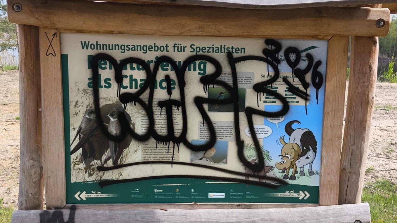 Blick auf eine Informationstafel am Bockwitzer See, die Unbekannte mit Graffiti zerstört haben