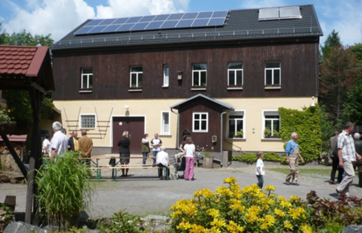 Zu sehen ist das Gebäude der Naturschutzstation Chemnitz Adelsberg. Im Vordergrund sind einige Besucher zu erkennen.