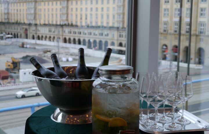 Im Vordergrund des Bildes sieht man die bereitgestellten Getränke für die Eröffnungsveranstaltung der Landesausstellung BNE. Im Hintergrund ist durch das große Fenster des Kulturpalastes  der Dresdner Altmarkt zu sehen.