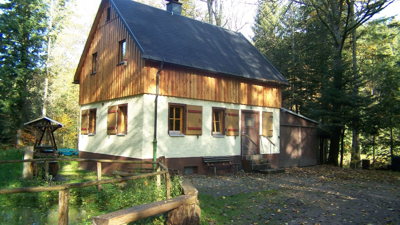 Zu sehen ist ein kleines zweistöckiges Waldhaus. Es dient dem Grüne Aktion Westerzgebirge e.V. als Waldstation.
