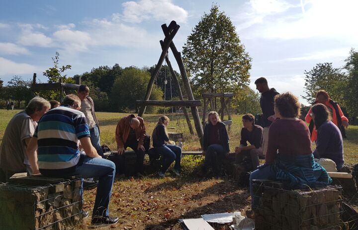 Teilnehmende eines Seminars im Freien sitzen im Kreis.