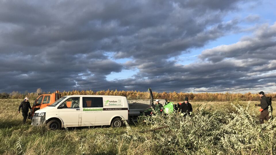 Mehrere Personen in Arbeitskleidung, dazu ein Kleintransporter und ein Multicar.